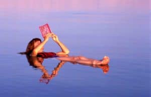 Woman floating on her back on the Dead Sea reading a book